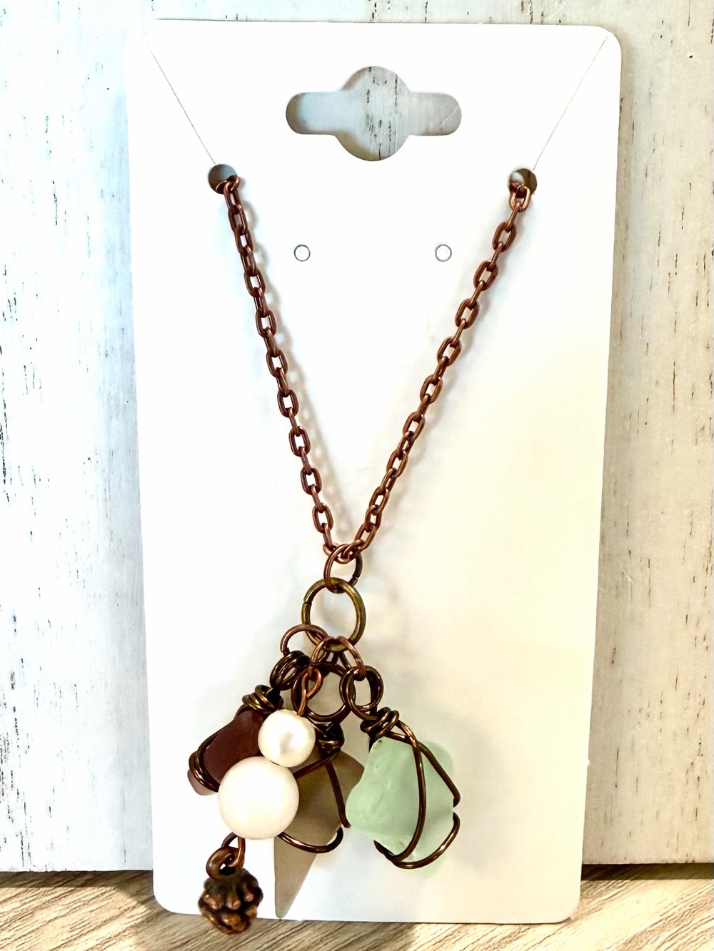 77. Multi colored sea glass pendant with a sunstone bead and pine cone charm